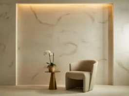 Elegant modern interior with Italian-style wall finish, featuring a marble-textured accent wall, beige curved chair, and a gold side table with a white orchid.